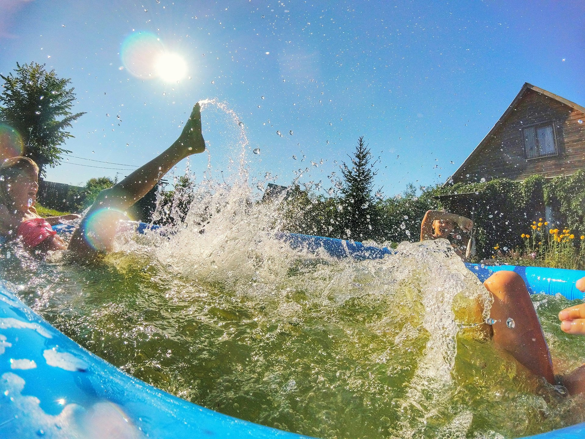Round inflatable swimming pool in a sunny garden with children playing