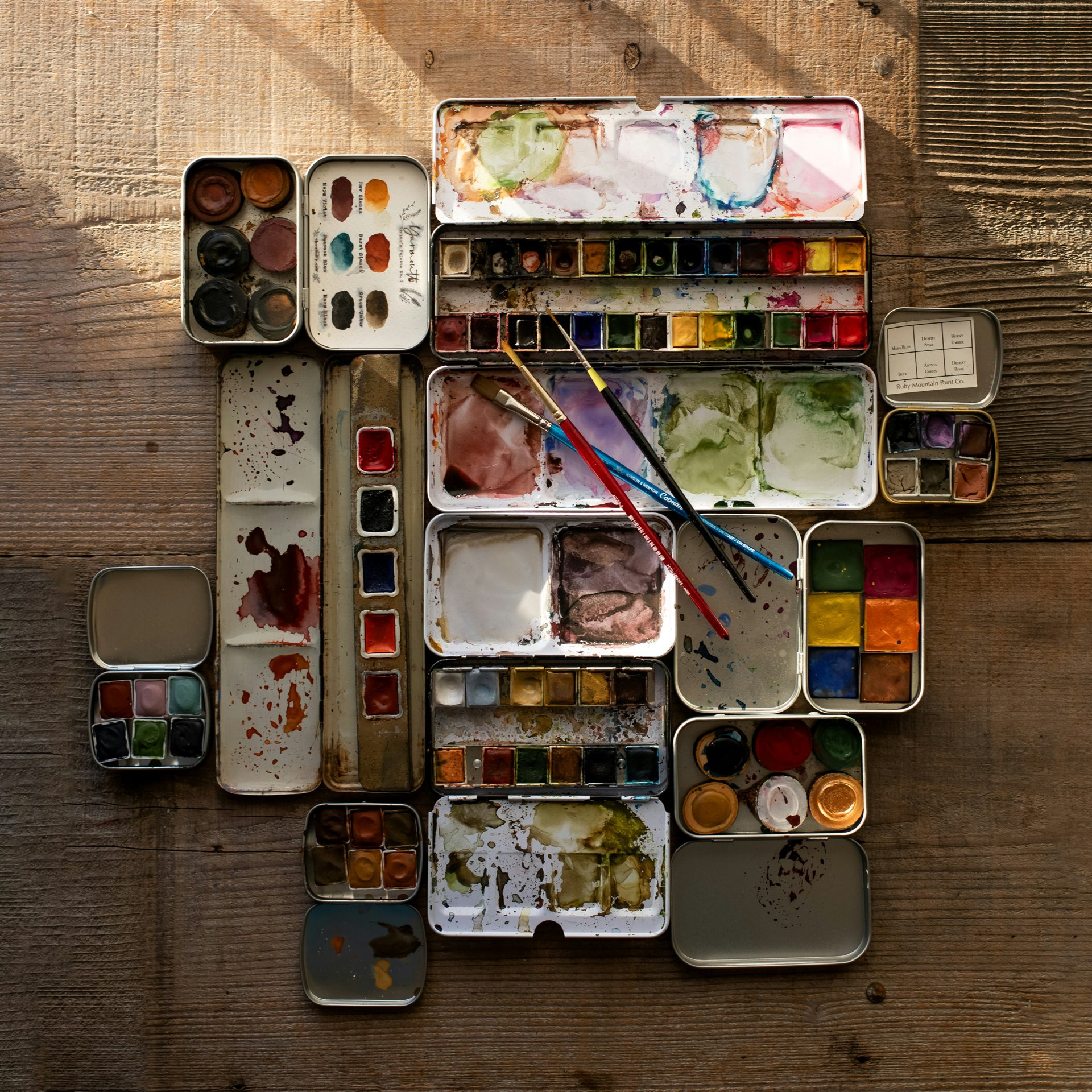 Paint tins and brushes on a wooden surface with colour swatches